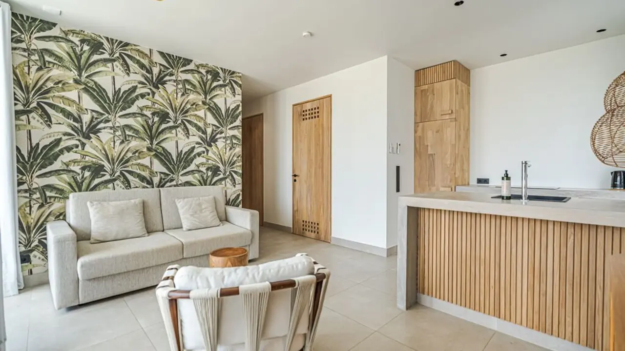 Bank en keukenblok voor een wand met palmenbehang in het 2-kamerappartement van Van der Valk Bonaire