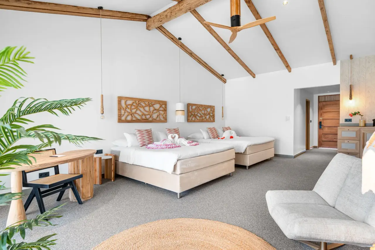 King Suite Ocean van Van der Valk Bonaire met twee kingsize bedden onder een houten balkenplafond met plafondventilator