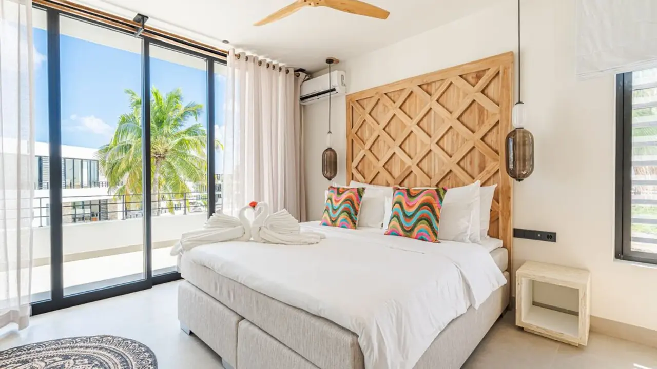 Slaapkamer met kingsize bed en toegang tot het balkon in het Penthouse Ocean View van Van der Valk Bonaire