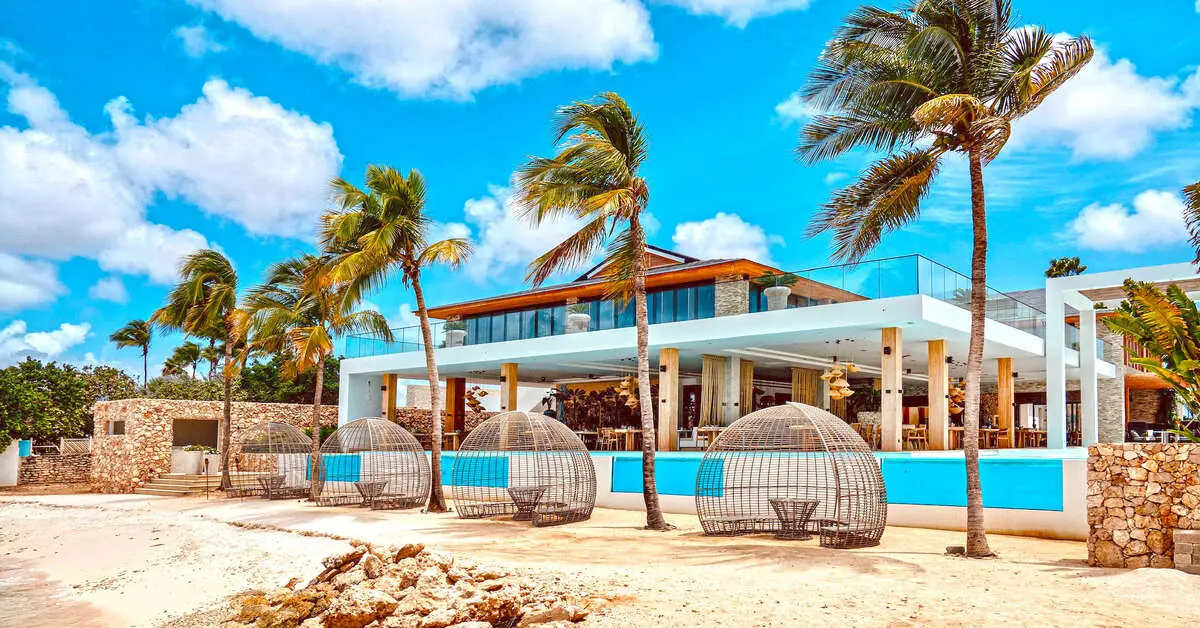 Hoofdgebouw van Van der Valk Bonaire met rieten strandcabana's op het zand