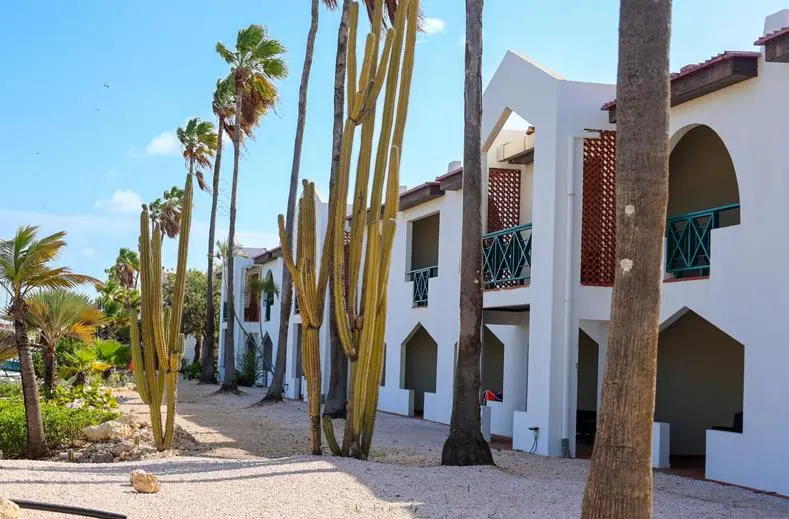 Oudere kamervleugel van Van der Valk Bonaire met witte bogen, balkons en cactussen
