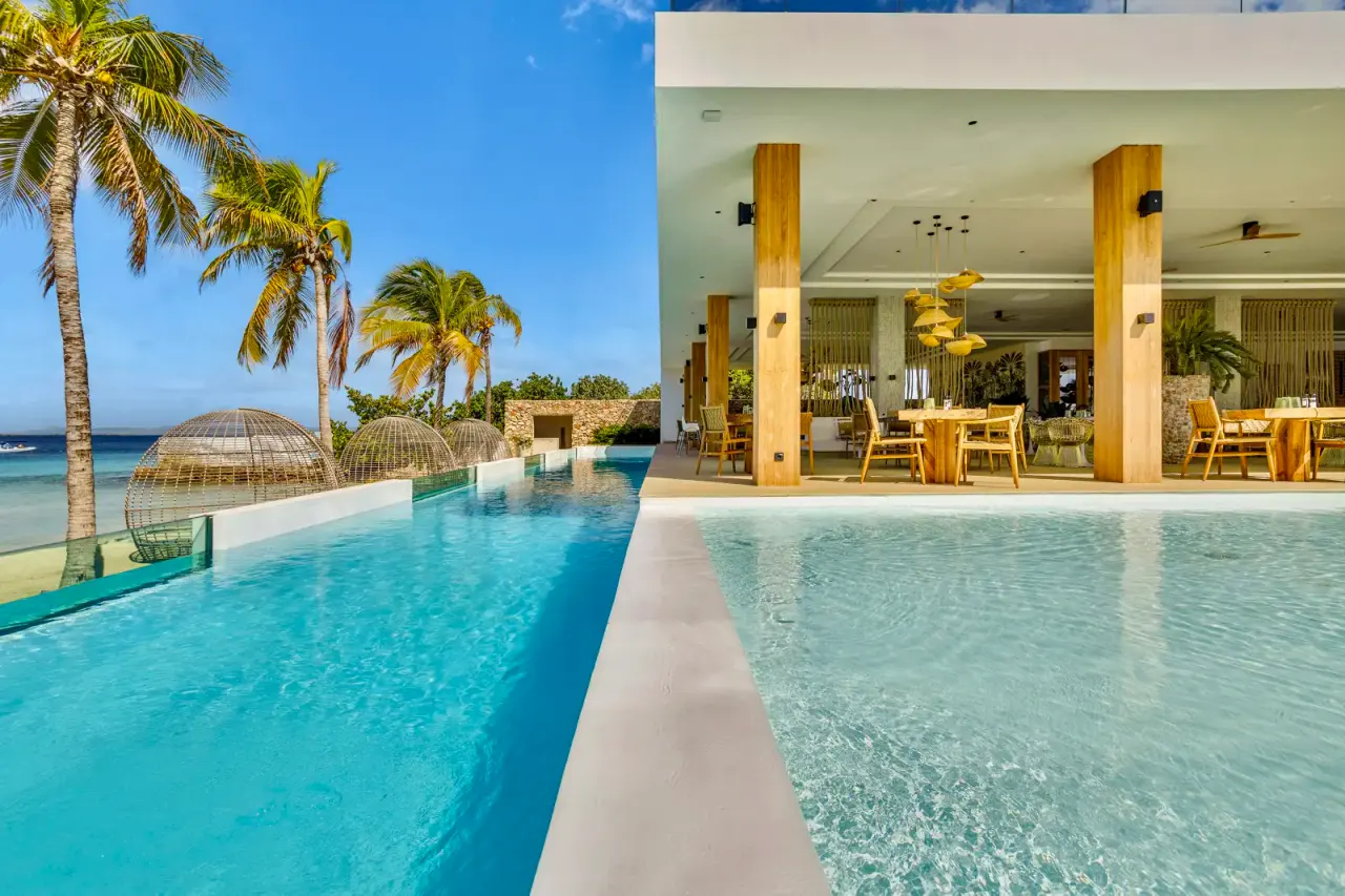 Zwembad langs het restaurant van Van der Valk Bonaire met palmbomen en zee